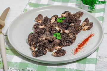 Raw black morel mushrooms with fresh parsley. Vegan ingredient for cooking healthy food