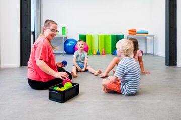 Children and female physical therapist during physical therapy session. Kids exercising barefoot...