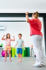 Kids group physio therapy. Children and female physical therapist exercising during session....