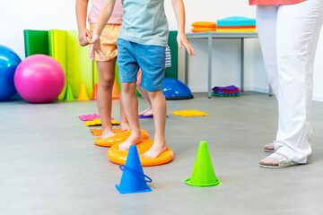 Kids physical therapy. Group of children and female therapist exercising during session. Bilateral coordination or integration.