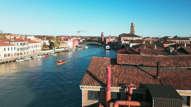 Captivating aerial footage of Murano&rsquo;s picturesque canals, historic bell tower, and charming buildings in Venice, Italy.