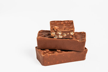 Several pieces of crunchy chocolate nougat in close-up and on a white background, a typical Christmas sweet.