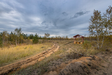 A dirt road with a wooden shelter in the middle of a field