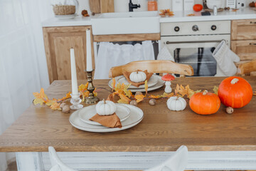 Decorative autumn dining table with pumpkins and fall leaves in a cozy kitchen setting