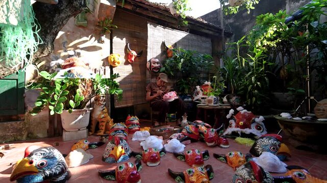 Old man making traditional Vietnamese paper mache masks in his house in Nam Dinh city, Vietnam