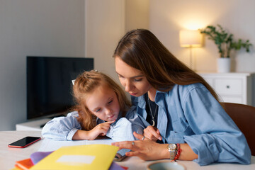 Young mother and daughter doing homework for elementary school