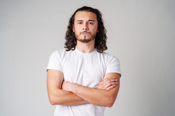 A young man stands thoughtfully against a plain background, expressing contemplation