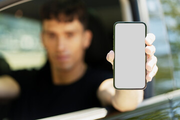 Man driving car showing smartphone with blank screen
