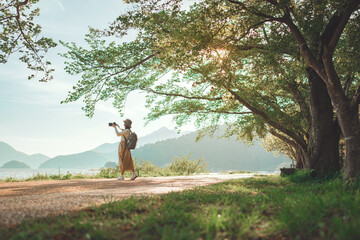 Young asian woman traveler photographer carrying camera and looking at distant natural view, in japan