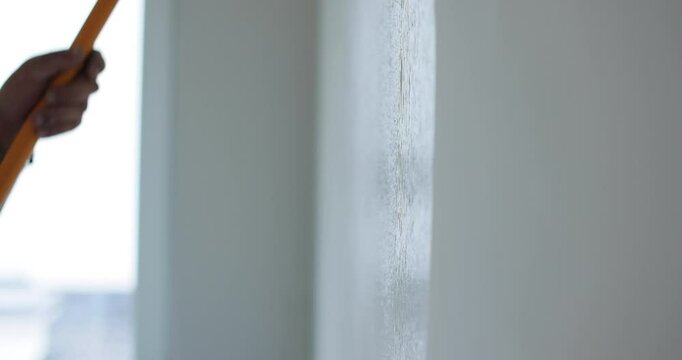 Man painter painting a house wall with a white paint roller. Painting and repair of the premises.