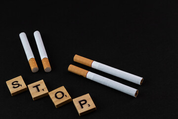 Cigarette and wooden blocks showing stop word on a black background.