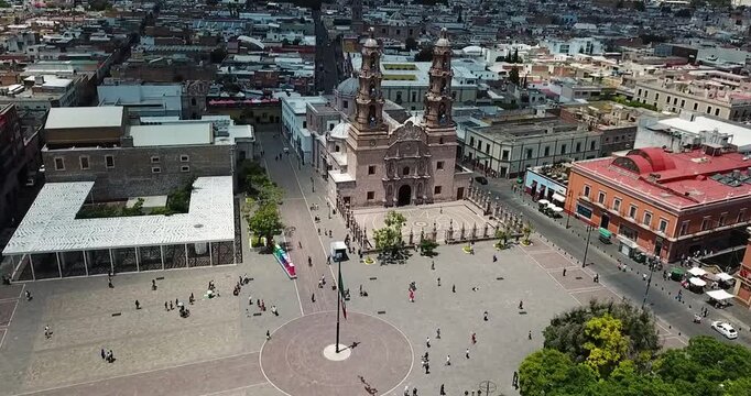 Flight over Plaza de la Patria approaching the Cathedral of Aguascalientes, Mexico, during the morning activities of a sunny Sunday