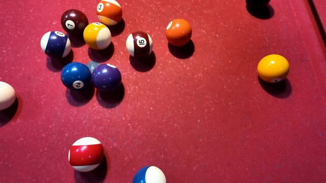 Colorful billiard balls scattered on a red pool table felt, related to leisure and recreation