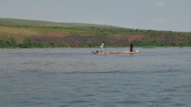 View of a fisherman silhouetted rowing a Congo traditional canoe on the waterways of the Congo river