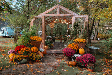 Charming garden greenhouse adorned with fall flowers and pumpkins in autumn