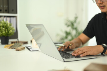 An architect or design professional typing on laptop working on a design project in a modern office