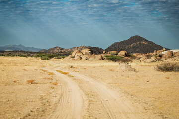 A winding dirt road through the arid landscape of Iona National Park in Angola under a dramatic sky