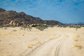 Exploring the rugged dirt road through Iona National Park in Angola under a vibrant sky