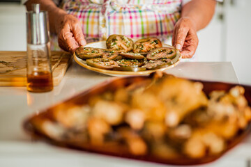 Elderly person preparing marinated tomato salad in the kitchen
