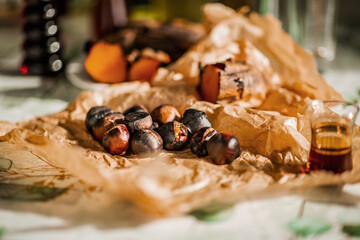 Roasted chestnuts on crumpled paper with glass of amber liquid in soft focus