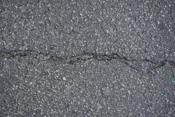 cracks on grey asphalt, repair of old road surface as background, wet pavement texture, gray asphalt texture with red and white gravels	
