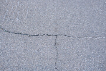 Obraz premium Cracks on grey asphalt close-up, old cracked asphalt close-up, old road surface bitumen 