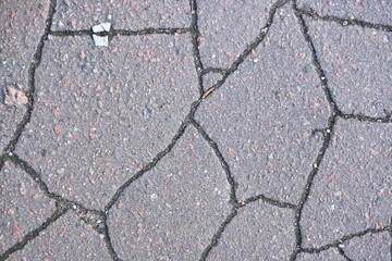 Obraz premium old cracked asphalt close-up, old cracked symmetrical pavement as a background, cracks on macro asphalt