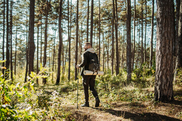 Obraz premium Young caucasian man hiking or trekking through the forest 