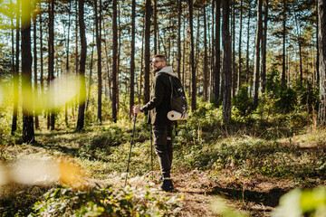 Young caucasian man hiking or trekking through the forest 