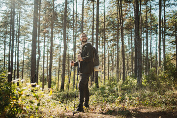 Young caucasian man hiking or trekking through the forest 