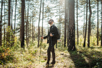 Young caucasian man hiking or trekking through the forest 