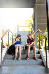 Obraz premium University students deep in study with notebooks and digital tools in stairs