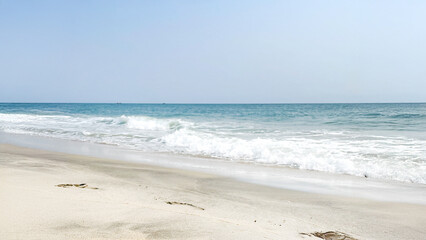Serene and empty beach with gentle waves under a clear sky, perfect for summer vacations and relaxation concepts