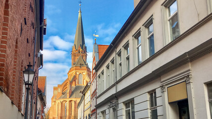 A picturesque view of a historic European church spire peeking above narrow cobblestone streets, evoking traditional Christmas architecture vibes