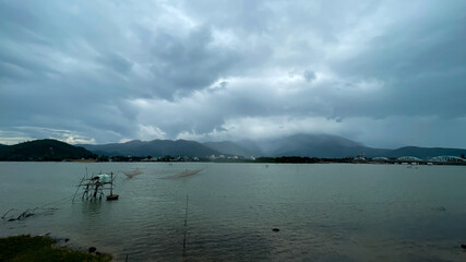 A serene landscape view of a lake under an overcast sky, illustrating the concept of tranquility and monsoon season