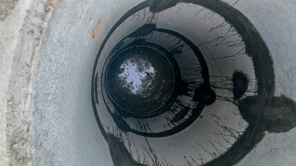 Looking down a concrete well illustrating water conservation challenges and resource management,...