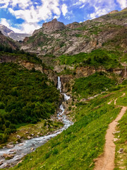 A serene mountain landscape with a cascading waterfall and lush green path symbolizes tranquility and adventure, ideal for Earth Day