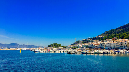 Fototapeta premium Scenic view of a Mediterranean coastal town with boats docked under a clear blue sky, ideal for summer vacation themes