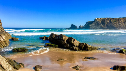 Scenic coastal view of a rocky beach under a clear blue sky, symbolizing relaxation and summer...