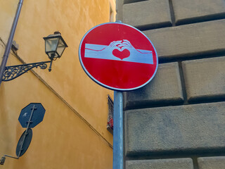 A creatively altered no-entry sign featuring hands holding a red heart symbolizes love and unity...