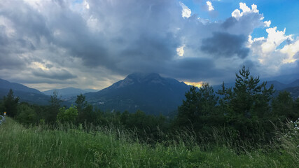 Fototapeta premium Dramatic storm clouds gather over a lush mountain landscape, evoking concepts of weather unpredictability and natural beauty