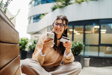 Young caucasian woman using credit card to buy online on her phone	