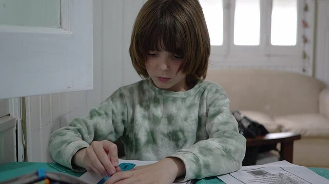 Close view of a little oy drawing a line with a ruler as part of his homework.