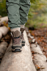 Young woman walking along fallen tree trunk in forest