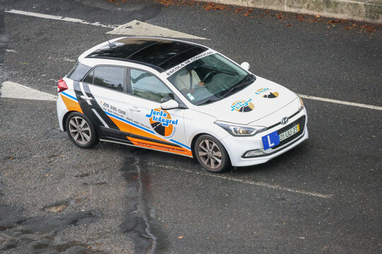 White driving school car driving on the street in odivelas portugal
