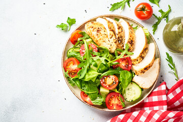 Green salad with grilled chicken meat at black table.