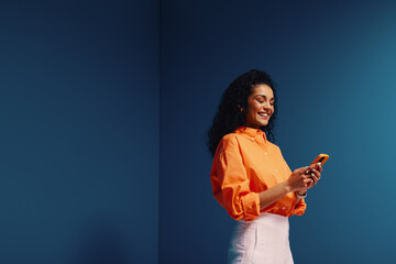 Happy woman scrolling on phone in vibrant monochromatic color blocking setting