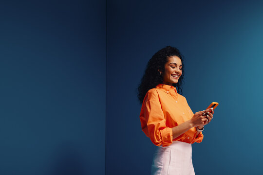 Happy woman scrolling on phone in vibrant monochromatic color blocking setting