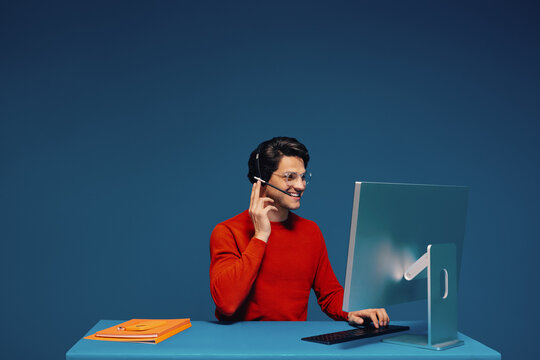 Male customer service agent working in monochromatic blue office