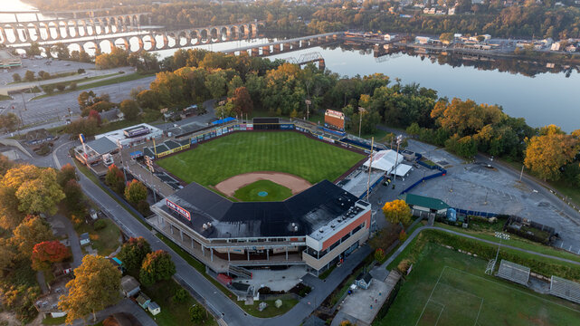 Aerial view of FNB Field in Harrisburg, Pennsylvania, located on an island, with the Susquehanna River and city bridges visible in the background during early morning light.